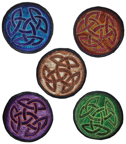 Five circular embroidered patches with Celtic knot designs in various colors on a white background.